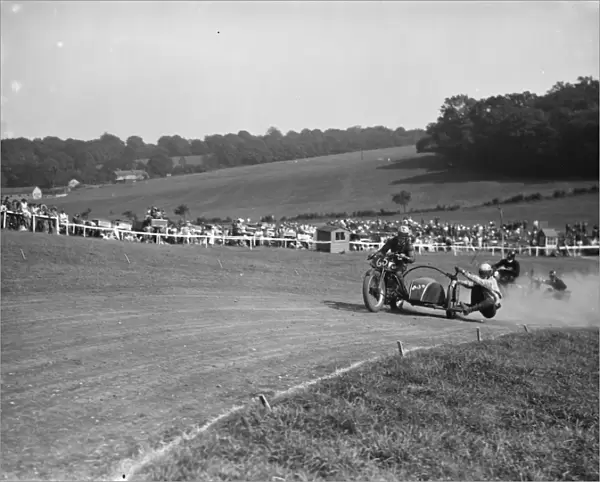 Motorcycling races at Brands Hatch. Two of the side car bikes jostle for position