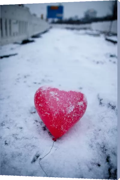 A red heart-shaped balloon lays in the snow on Februray 14, 2012 in Frankfurt  /  M. western Germany