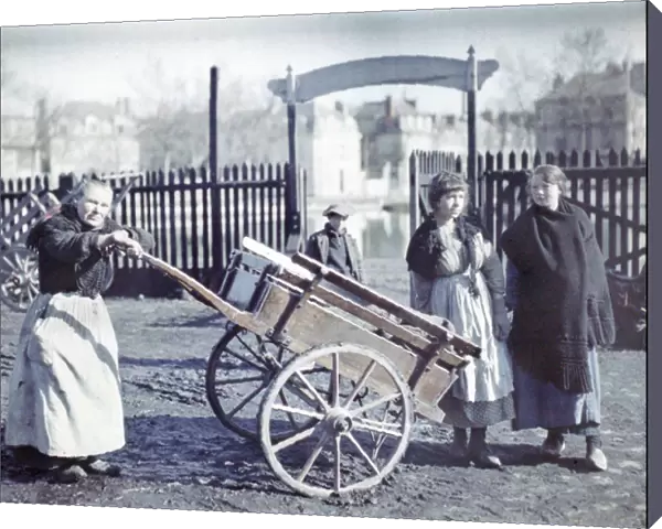 Old woman with a cart on a muddy road, with two girls and a boy, France, c