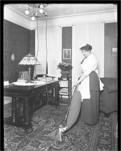 Unidentified woman demonstrating the use of the Apex vacuum cleaner, c