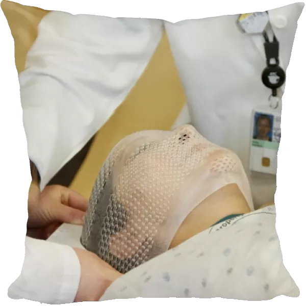 Radiation therapists fit a short face mask to a patient during radiation therapy