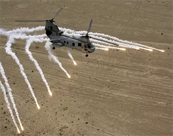 A U. S. Marine Corps CH-46 Sea Knight helicopter launching flares over the desert near Al Taqqadum