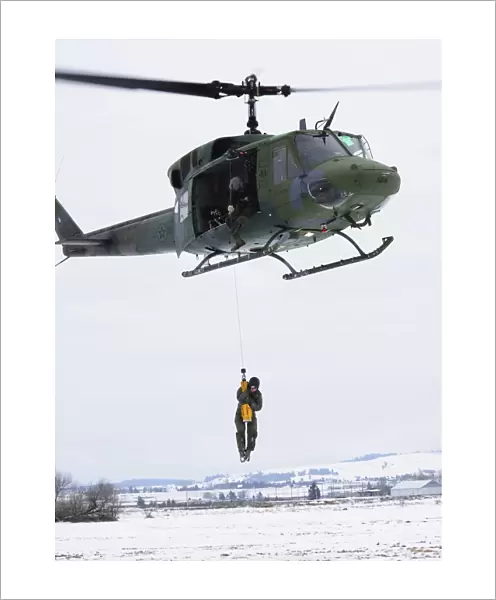 A student is hoisted into a UH-1N Iroquois during a training exercise