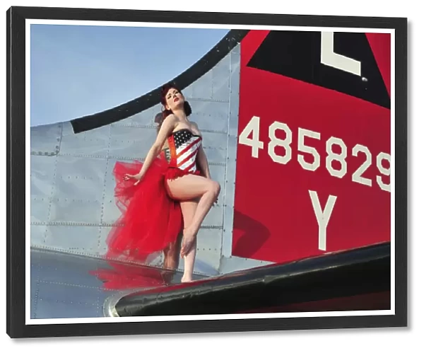 1940s style pin-up girl standing on the tail of a B-17 bomber