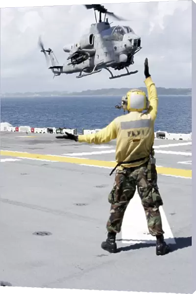 Airman directs an AH-1W Super Cobra onto the flight deck of USS Essex