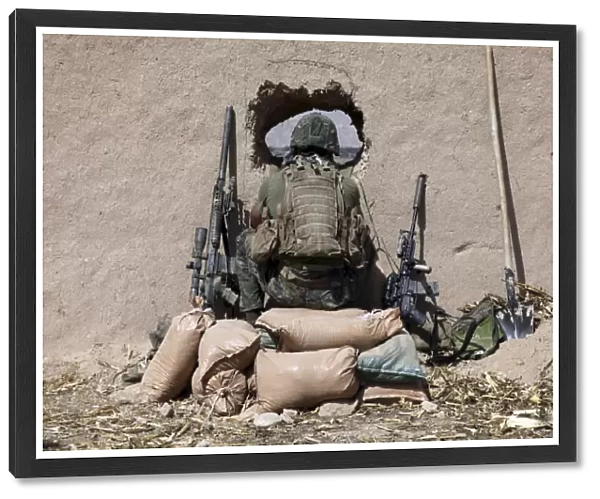 A U. S. Marine sniper observes his sector at a patrol base near Sangin, Afghanistan