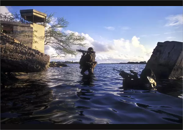 A pair of Navy SEAL combat swimmers transition from underwater to the surface