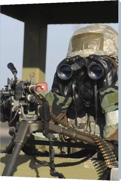 A soldier looks through binoculars from his outpost