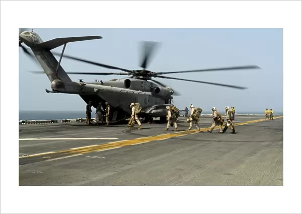U. S. Marines prepare to board a CH-53E Super Stallion helicopter aboard USS Peleliu