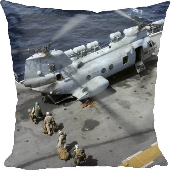 U. S. Marines board a CH-46 Sea Knight helicopter on the flight deck of USS Peleliu