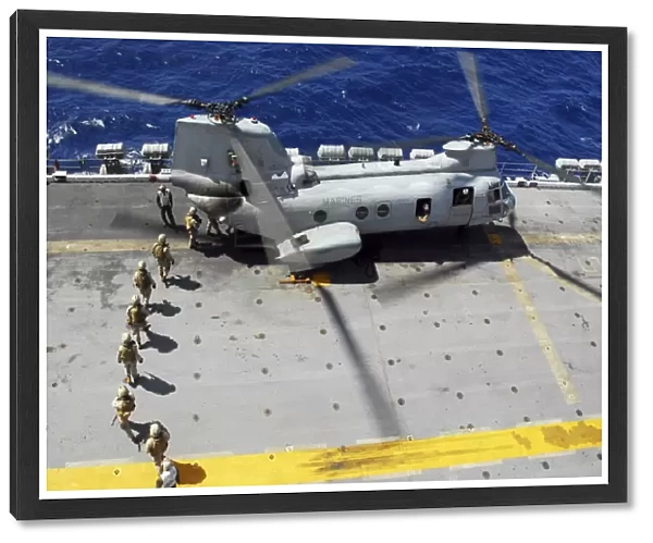 Marines board a CH-46E Sea Knight helicopter on the flight deck of USS Peleliu