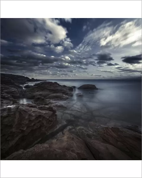 Huge rocks on the shore of a sea against a cloudy sky, Sardinia, Italy