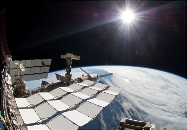 The bright sun, a portion of the International Space Station and Earths horizon