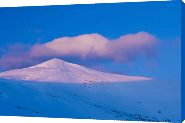 A snowy mountain peak lit by low crepuscular light before sunset. Ordesa National Park