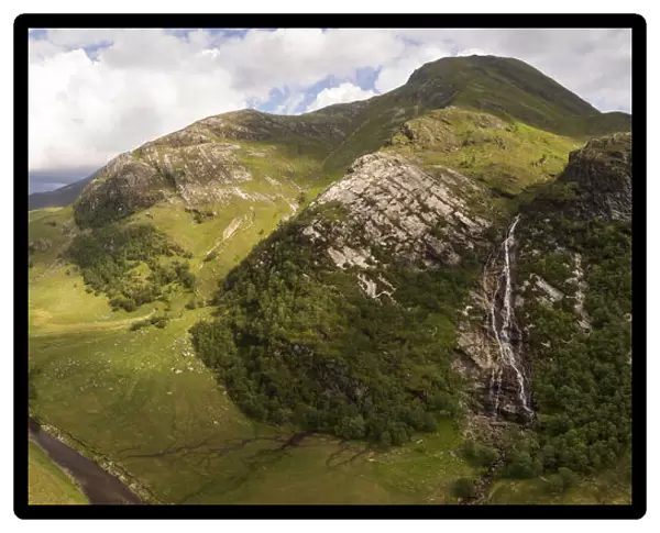 Aerial view of Steall waterfall lined by Birch (Betula pendula) woodland and river running through Glen Nevis, Highlands, Scotland, UK. June, 2018