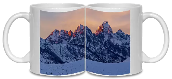 The last rays of sunset hit the Grand Teton and adjacent peaks on a winter evening. Grand Teton National Park, Wyoming, USA