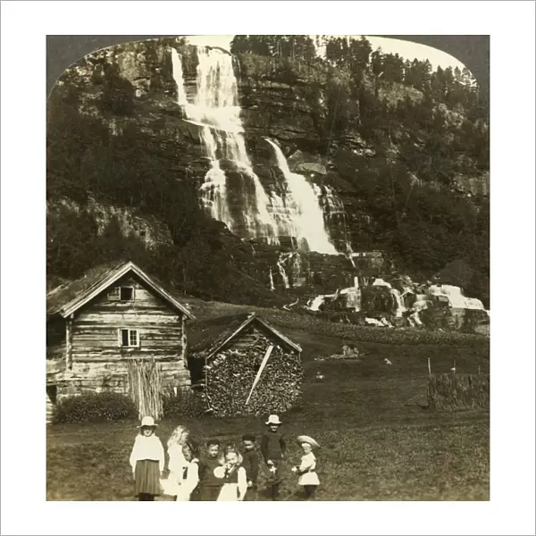 Children at play in a farmers field with terraced Tvinde waterfall, Vossevangen