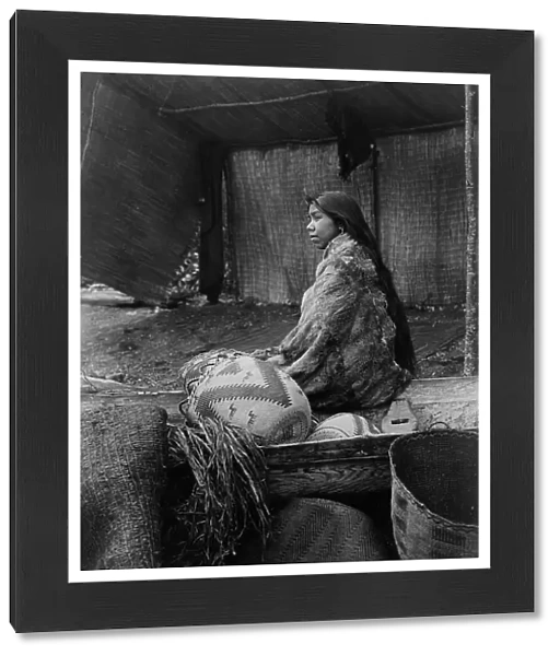 A Skokomish Indian chief's daughter, half-length portrait, seated on canoe, facing left, c1913. Creator: Edward Sheriff Curtis