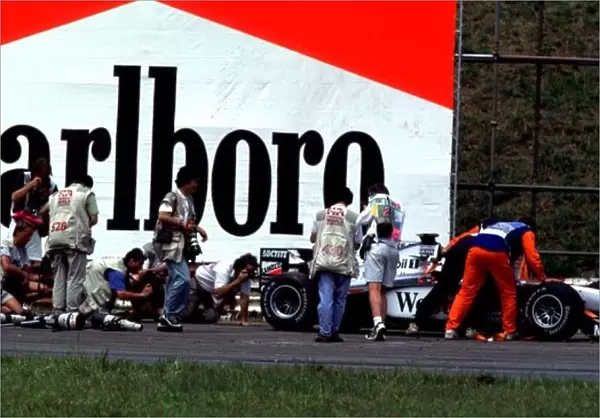 1998 BRAZILIAN GP. Photographers crowd round a stranded McLaren out on the track for