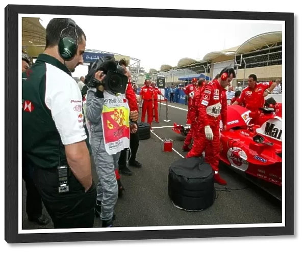 Formula One World Championship: Ben Agathangelou Jaguar Head of Aerodynamics has a look at the car of Michael Schumacher Ferrari F2004 on the grid
