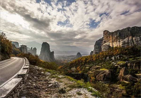 Landscape Of Rugged Cliffs, Road, Autumn Foliage And Monastery Rousanou In The Distance; Meteora, Greece