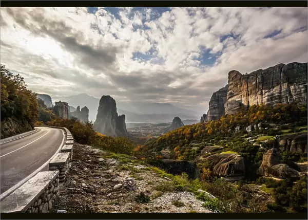 Landscape Of Rugged Cliffs, Road, Autumn Foliage And Monastery Rousanou In The Distance; Meteora, Greece