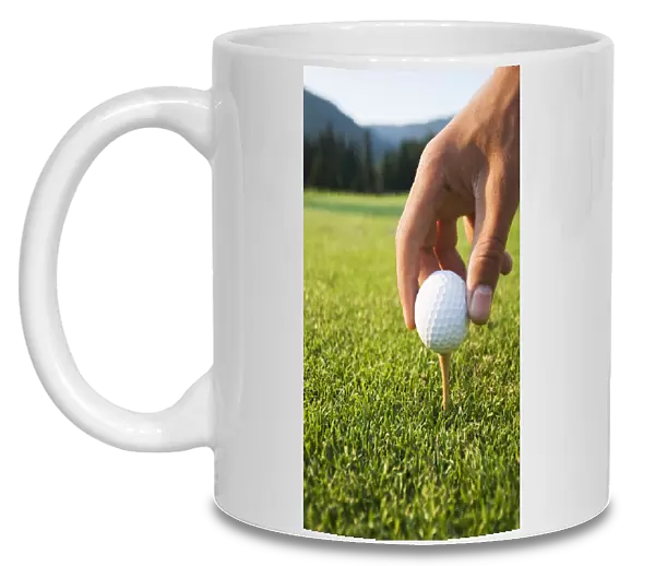 Golfer Sets Up A Ball On The Tee Of A Golf Course On A Summer Evening; Whistler, British Columbia, Canada
