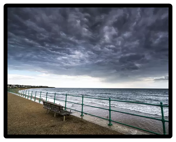 Green Metal Railing And Bench Along The Water Under Dark Storm Clouds; Sunderland, Tyne And Wear, England