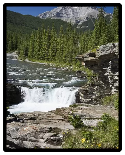 Waterfalls With Rock Ledge And Mountain In The Background; Alberta, Canada