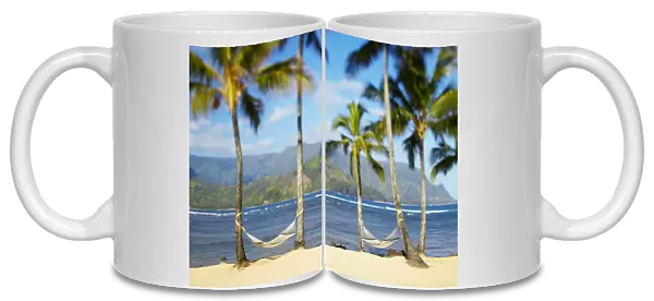 USA, Hawaii, Kauai, Two hammocks hanging between palm trees on sandy tropical beach; Hanalei Bay Princeville