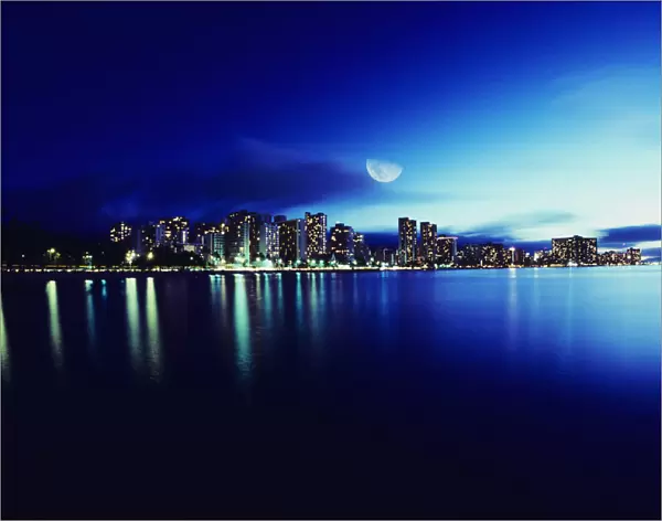 Hawaii, Oahu, Honolulu, Waikiki skyline at night, moon overhead, view from ocean