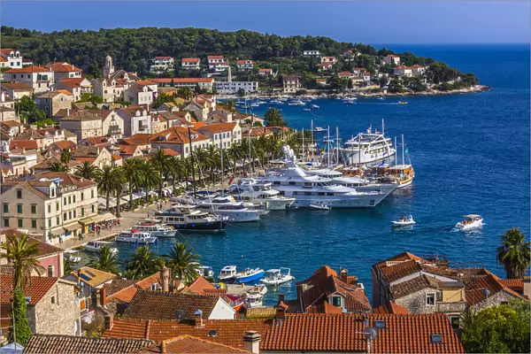Overview of clay tile rooftops and luxury yachts docked in marina at the Old Town of Hvar on Hvar Island, Croatia