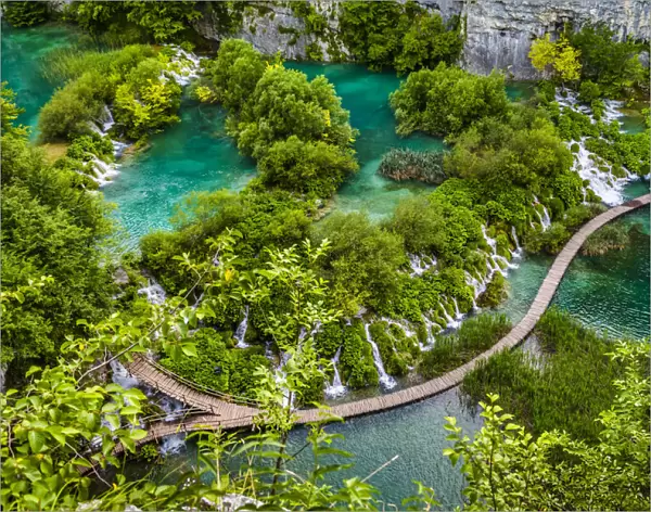 Footbridge crossing the turquoise lake water and waterfalls at the Plitvice Lakes National Park, Croatia