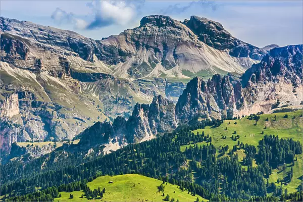 Scenic vista of the grassy mountain side and the jagged mountain tops at the Sella Pass in the Dolomites in South Tyrol, Italy