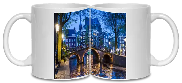 Stone bridge lit up at dusk along the Leidsegracht Canal in Amsterdam, Holland