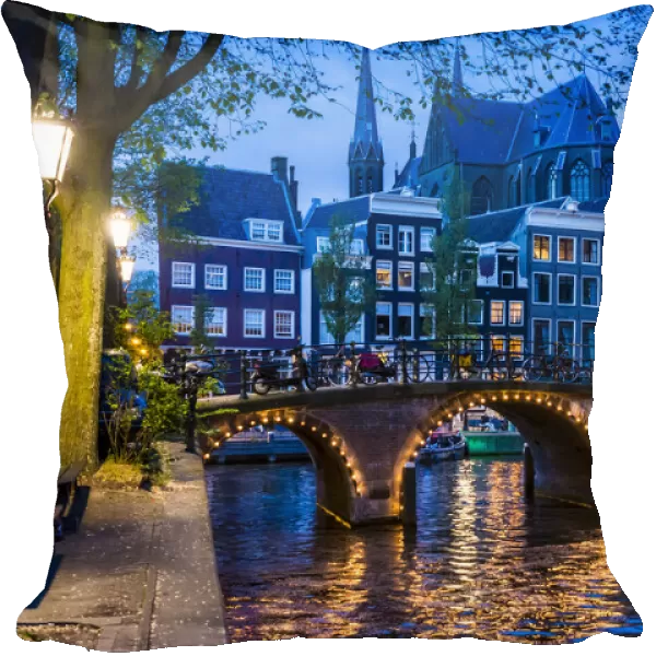 Stone bridge lit up at dusk along the Leidsegracht Canal in Amsterdam, Holland