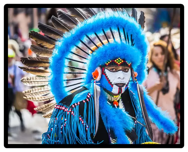 Portrait of male, indigenous tribal dancer wearing blue feathered headdress and looking at the camera in the St Michael Archangel Festival parade in San Miguel de Allende, Mexico