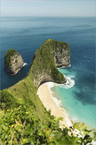 Green covered rock formation jutting out into the ocean, Klungkung Beach, Nusa Penida, Indonesia
