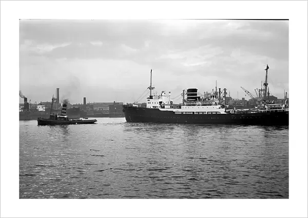 Bergen line ship Astrea leaving the tyne in the late 1940s early 1950 s. Towed by a tyne tug passing the Customs house, Mill Dam and St. Hildas colliery; South Shields, Tyne and Wear, England