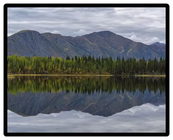 Beautiful reflection of the St. Cyr mountain range in Jackfish Lake; Ross River, Yukon, Canada
