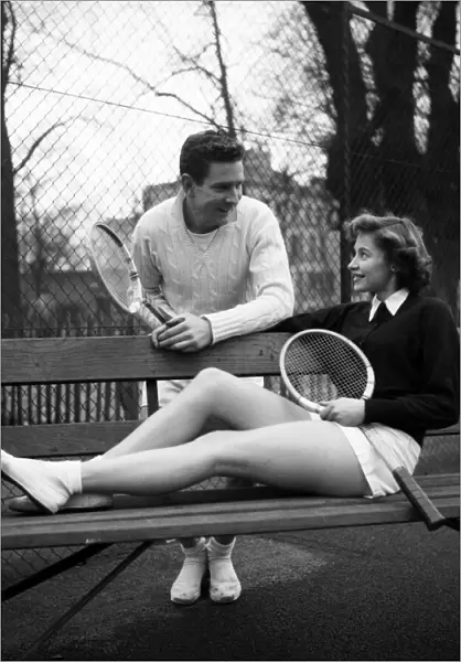Man and woman talking on a park bench after enjoying a game of tennis January