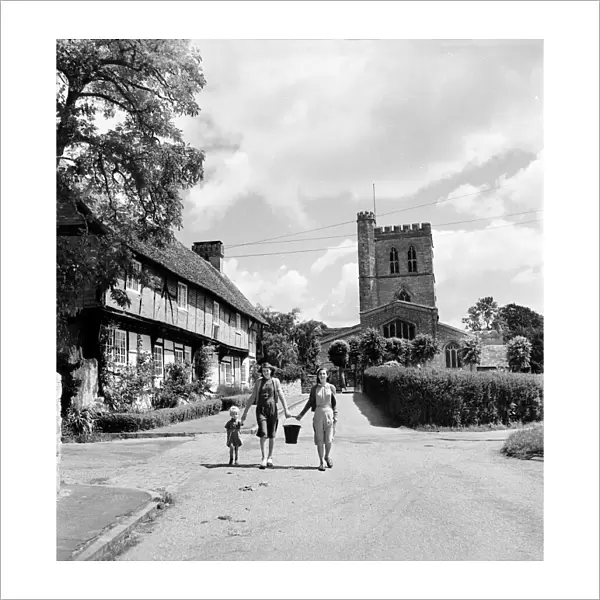 A family walk down the street in the village of Long Crendon, Buckinghamshire