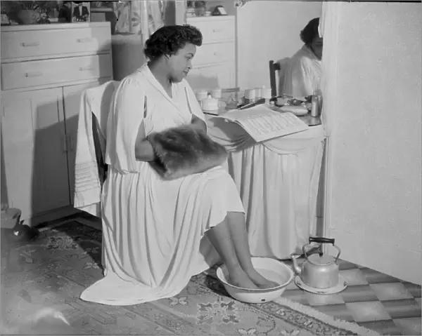 Winifred Atwell, pianist, puts her feet into bowl of hot water