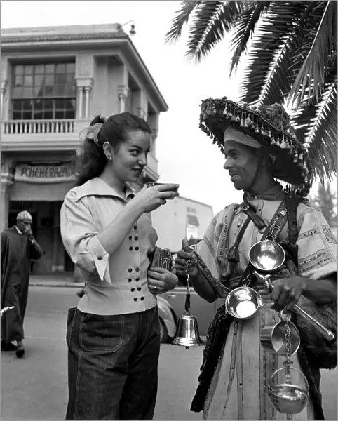 French actress buys a drink of water from a local vendor in the town of