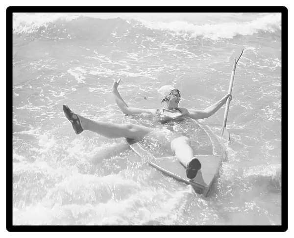 Woman playing in the surf with a canoe at Elmer Sands, West Sussex