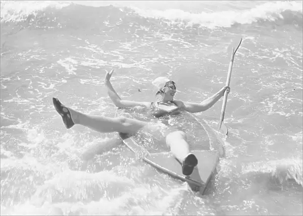 Woman playing in the surf with a canoe at Elmer Sands, West Sussex