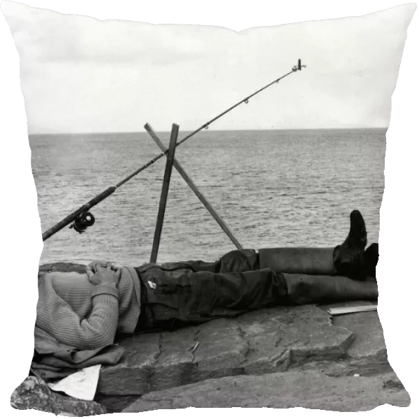 Fishing - A fisherman takes a nap whilst fishing of some rocks - South Wales - 24th July