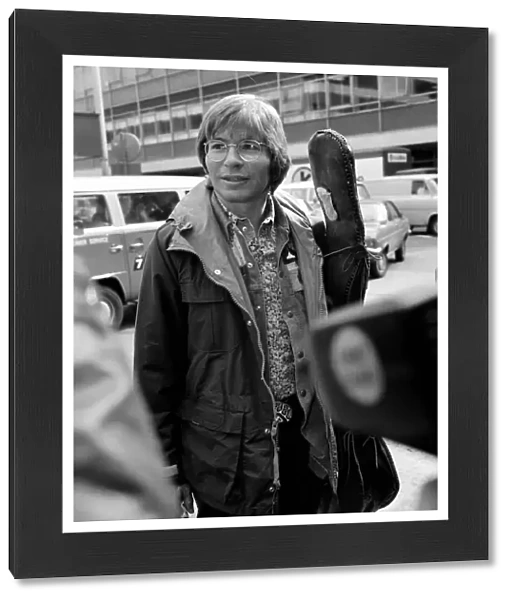 John Denver: U. S. singer seen here at London Airport with his guitar. April 1976