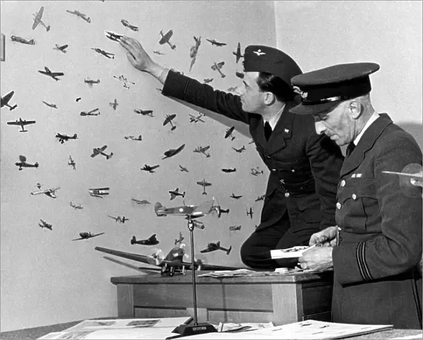 An RAF officer preparing cut outs of enemy planes from magazines to stick on the walls of