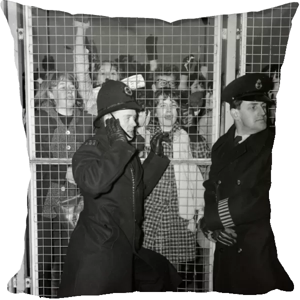 Excited female Beatles fans deafen a young policeman keeping them at bay before